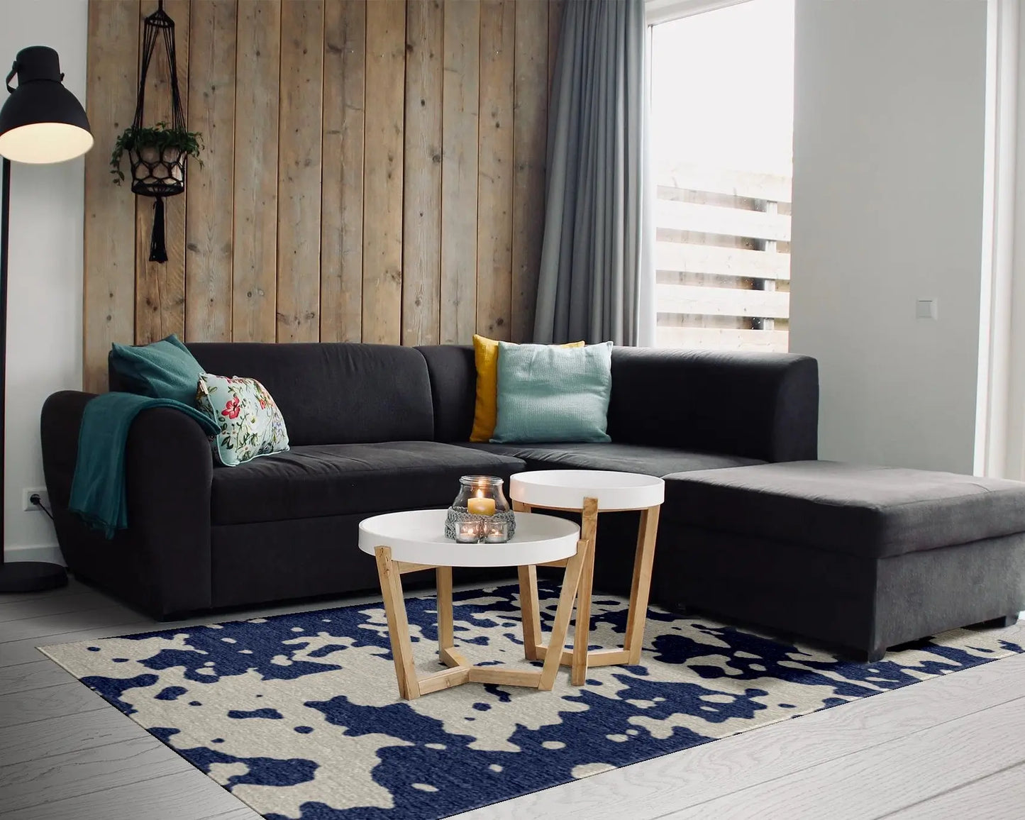 Modern living room with a black sectional sofa, colorful cushions, and a patterned rug.