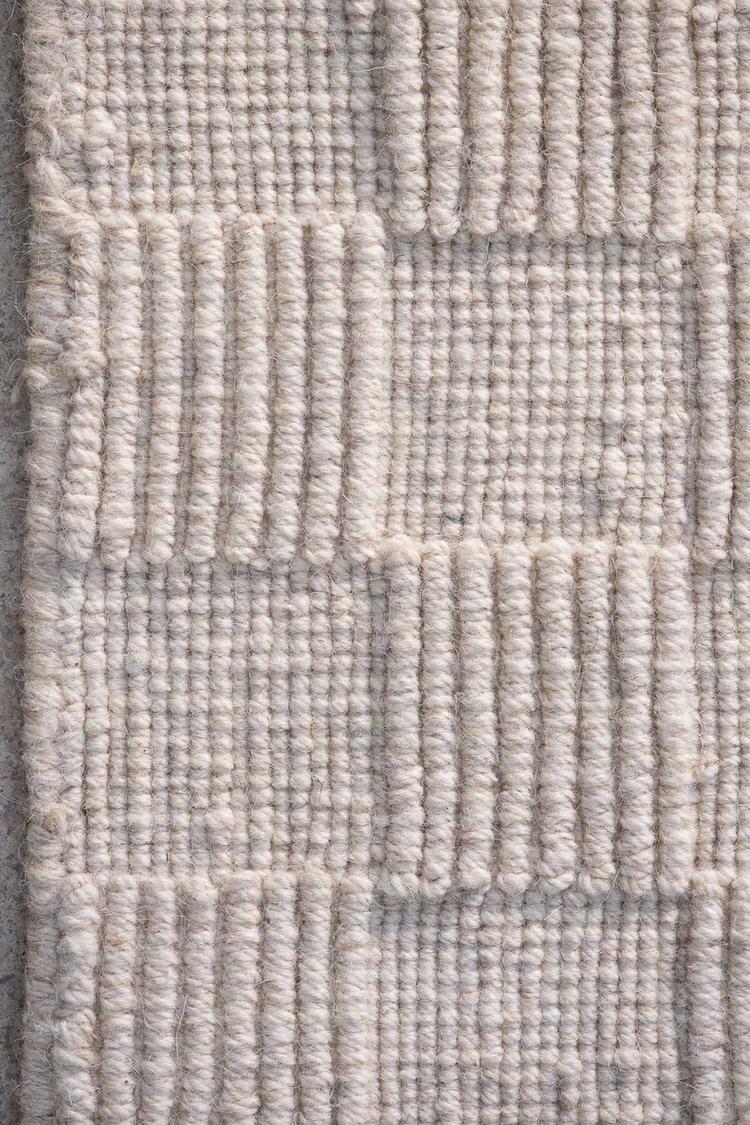 close view of off white handloom rug, showing square pattern design