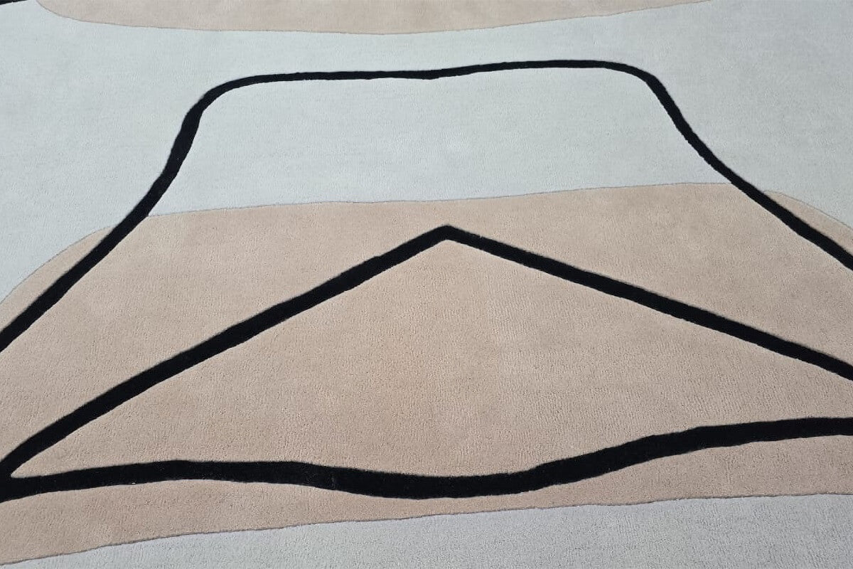 Hand tufted rug with black abstract line design on a neutral background