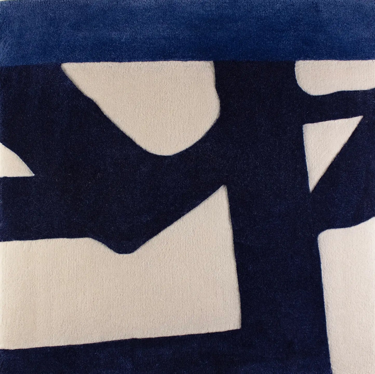 Close-up of a blue patterned wool rug with abstract shapes