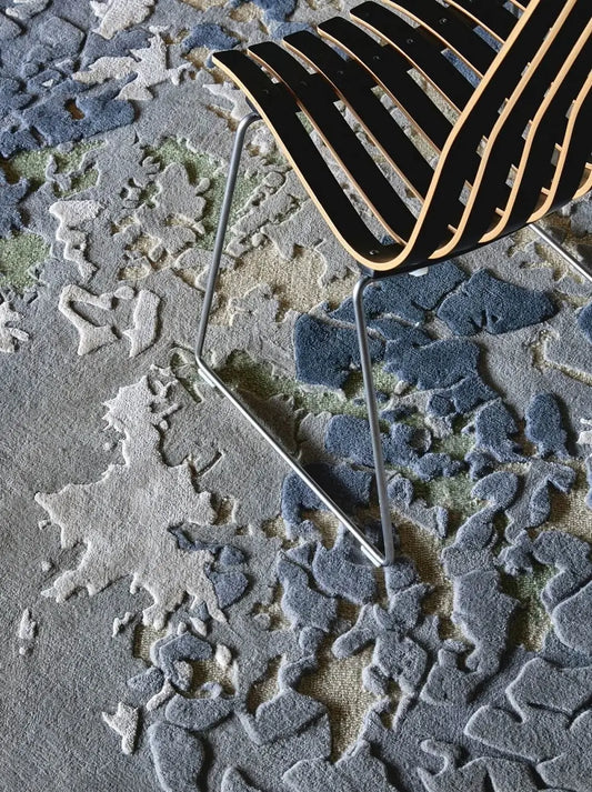 Close-up of a textured premium wool and silk carpet with a metal chair.