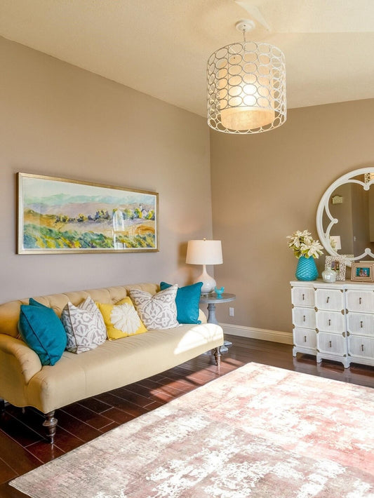 blush hand woven rug in living room with beige sofa, colorful pillows, and decorative items.
