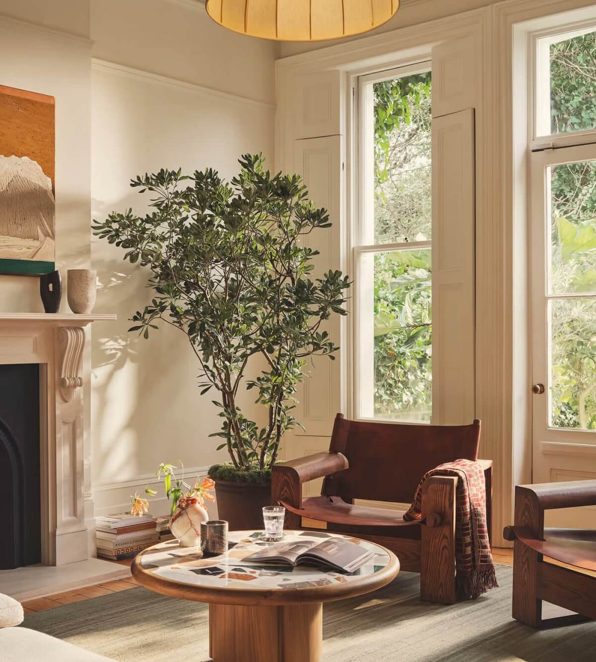 Living room with a handwoven rug, potted plant, wooden table, and chair near a fireplace.