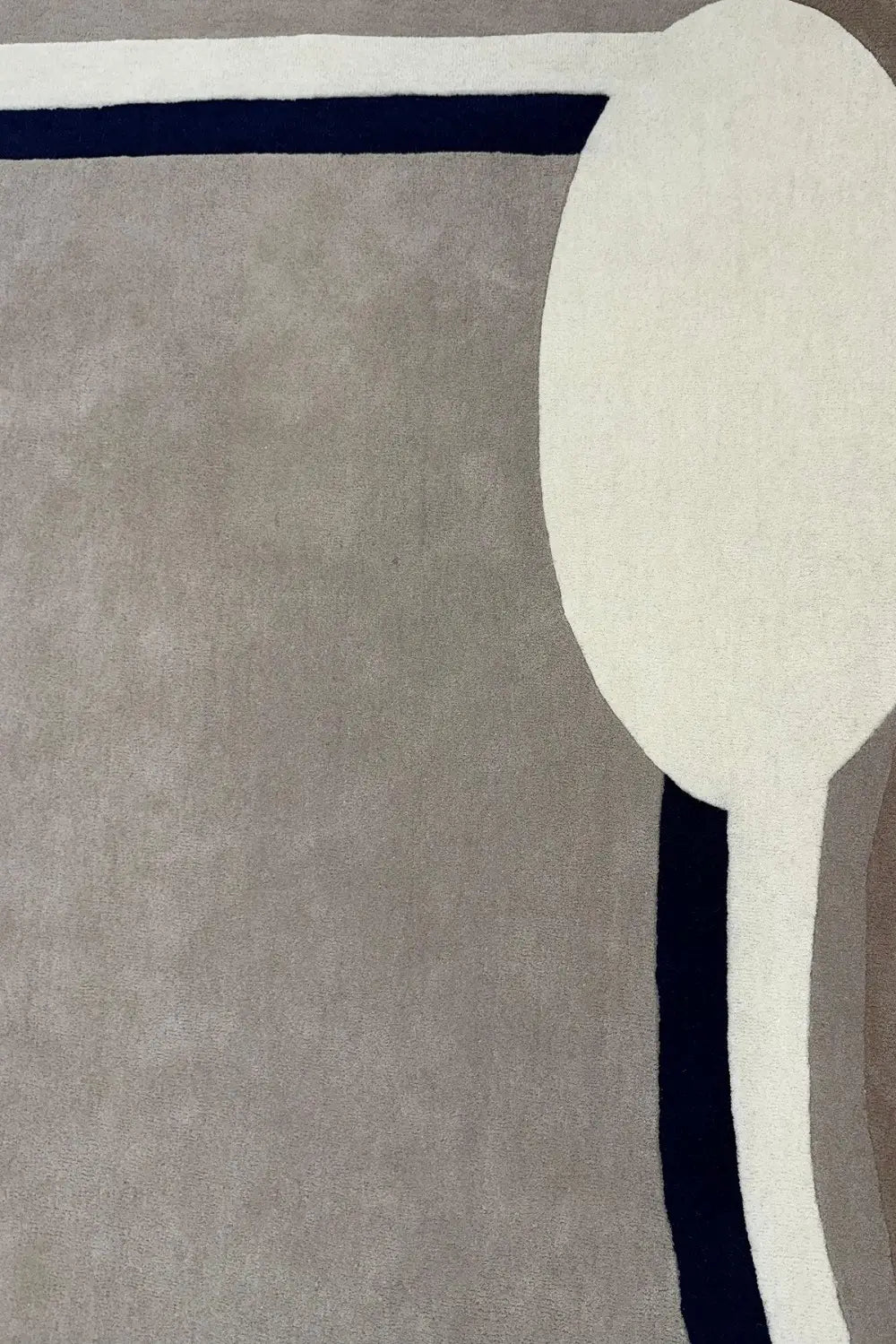 Close-up of gray hand tufted wool rug with a white border and a blue accent line