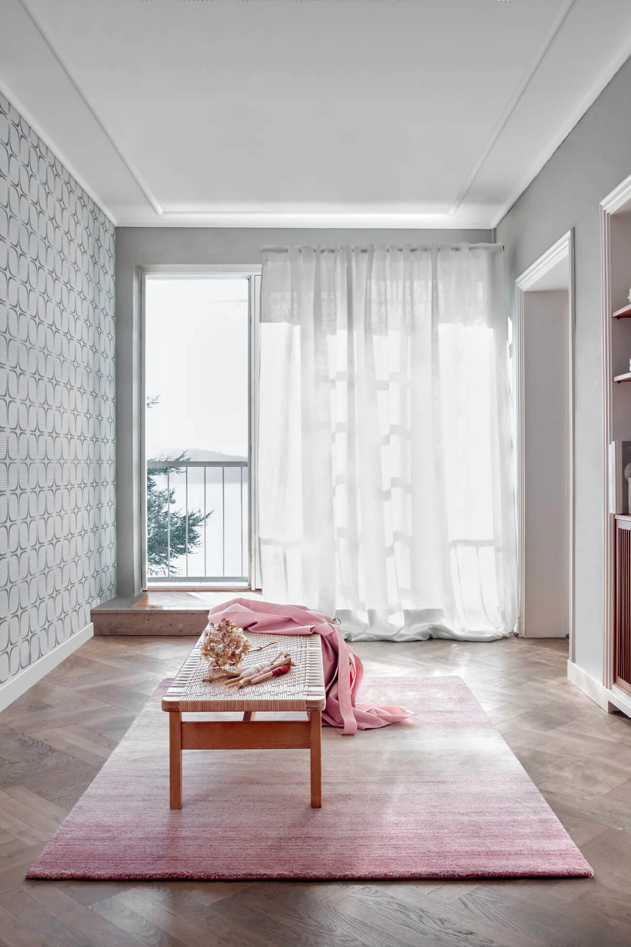 Modern interior with hand wovwn wool rug, wooden coffee table, and white curtains