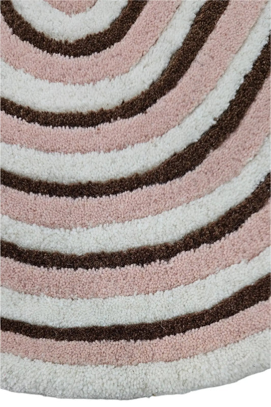 Close-up of a hand tufted textured wool rug with concentric circular patterns in beige, brown, and white.
