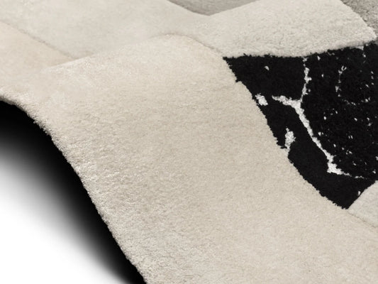 Close-up of textured hand tufted wool rug with a black abstract design on a light gray background