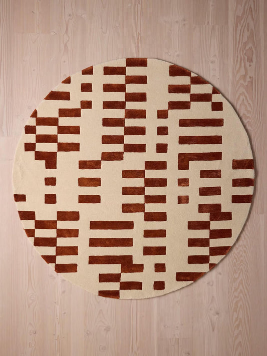 Round rug with brown and beige checkered pattern on a wooden floor