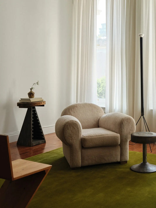 a room with green hand tufted wool carpet and beige armchair