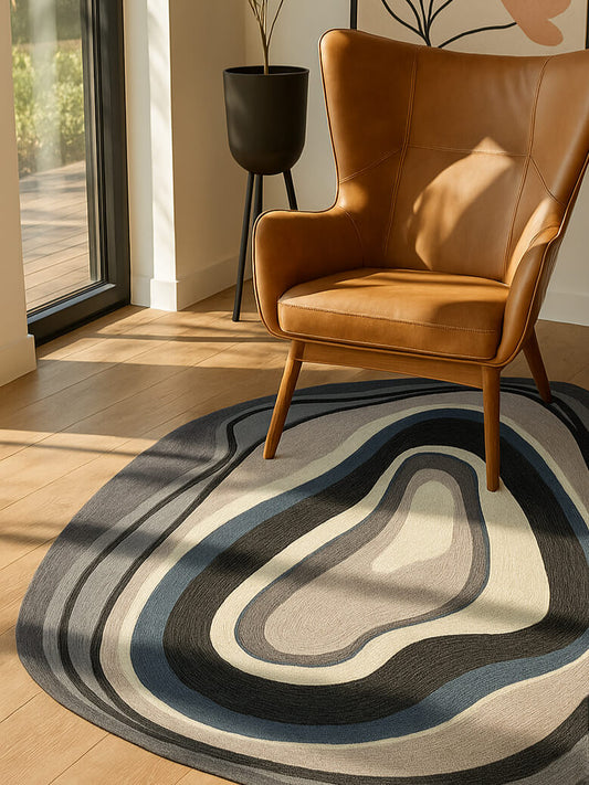 Brown leather armchair on a wavy hand tufted shaped rug in a room with a window and plant.