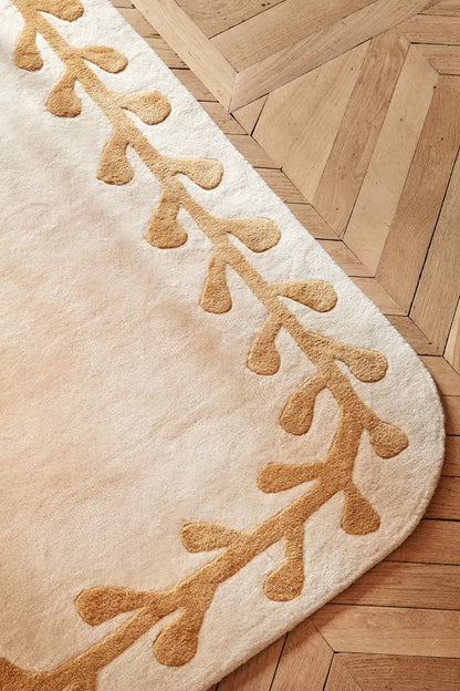 Beige rug with brown leaf pattern on a wooden floor
