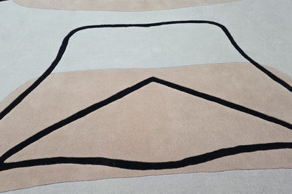 Hand tufted rug with black abstract line design on a neutral background