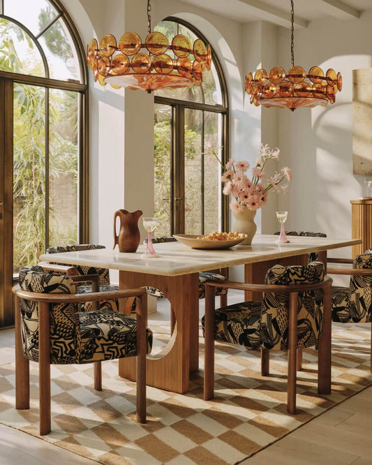 hand woven pettern rug in dining room with wooden table, patterned chairs, and decorative lighting.