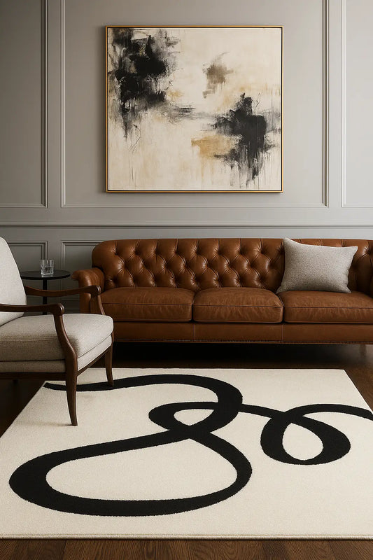 Bisa black hand tufted wool rug in living room with brown leather sofa, white armchair and abstract painting.