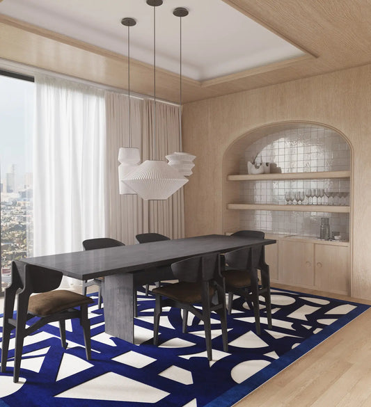 Modern dining room with a long table and chairs on a blue geometric hand tufted wool rug.