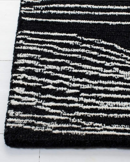 Close-up of a black and white wave line rug on a white floor.