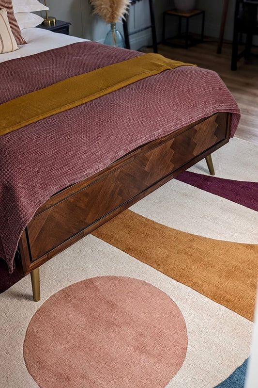 Wooden bed with a pink blanket on a modern hand tufted geomatery area rug