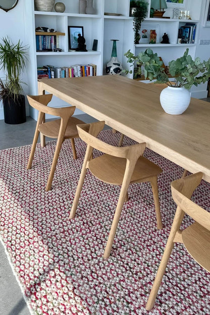 hand woven patterned wool rug in a dining room with shelves and decor.