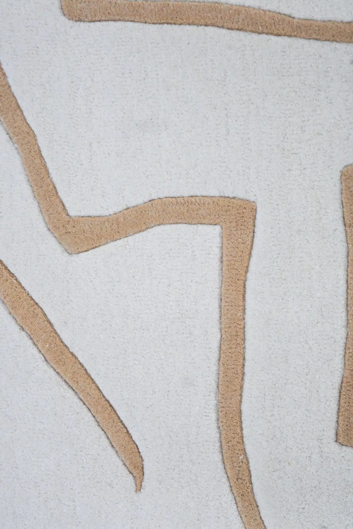 Close-up of modern rug with beige geometric patterns on a light gray background