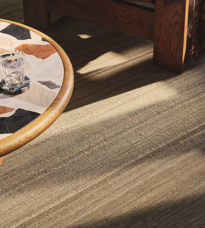 Close-up of a hand woven textured carpet with a wooden table