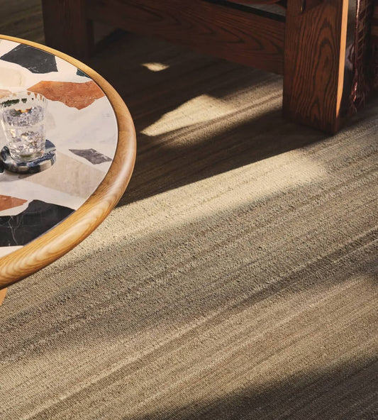 Close-up of a hand woven textured carpet with a wooden table