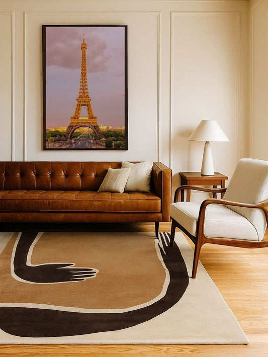 Living room with modern hand tufted woolrug, brown leather sofa, white armchair, and Eiffel Tower artwork on wall.