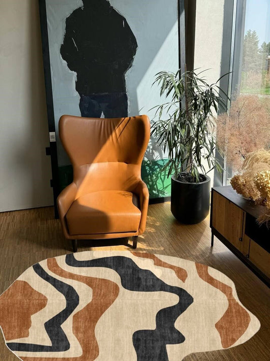 Orange armchair in a room with a hand tufted patterned shaped rug, plant, and cabinet.