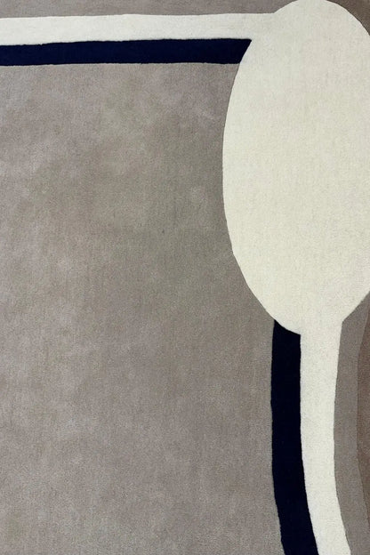 Close-up of gray hand tufted wool rug with a white border and a blue accent line