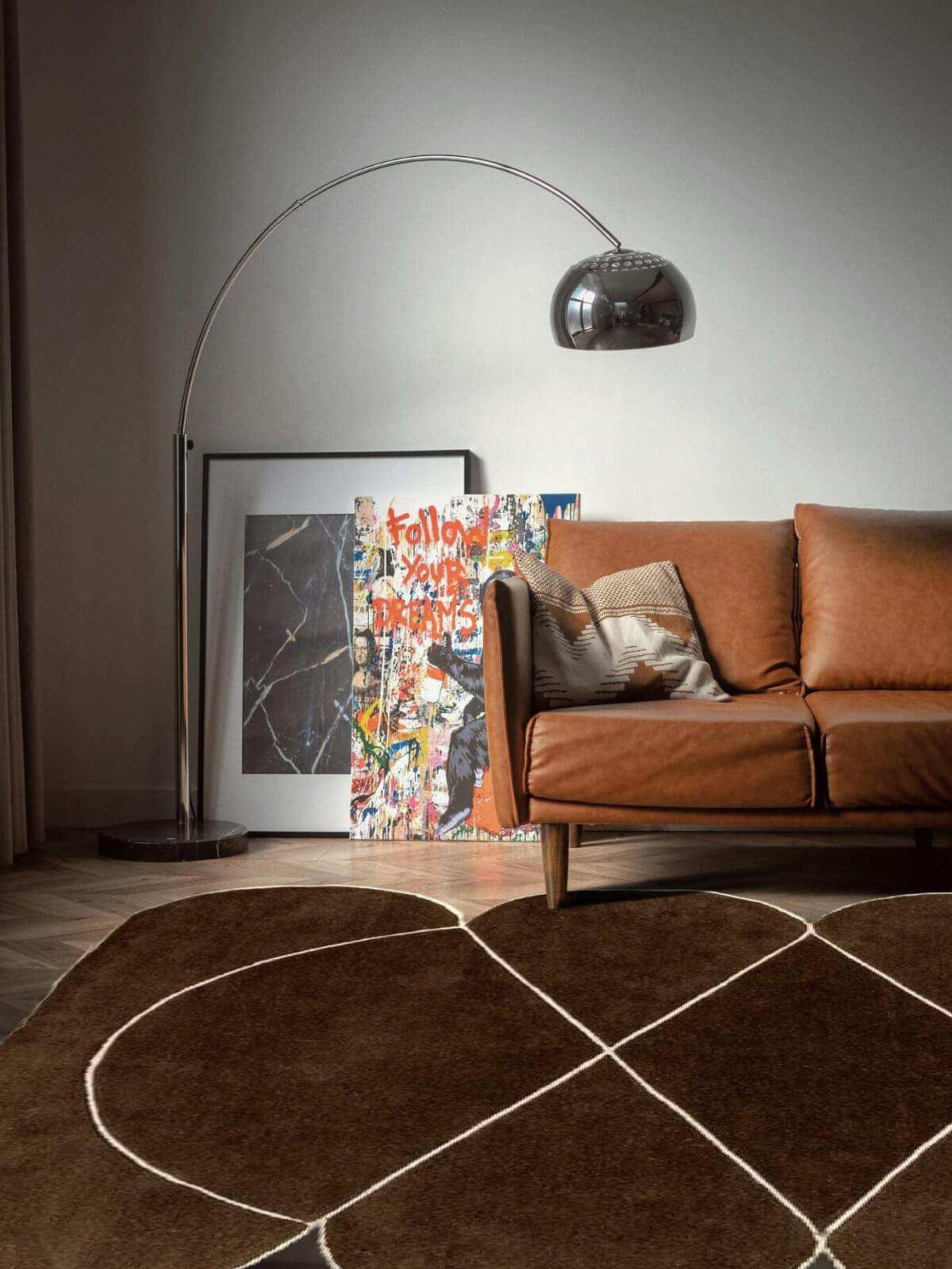 modern brown wool rug and leather sofa in a living room with a floor lamp and artwork on the wall.