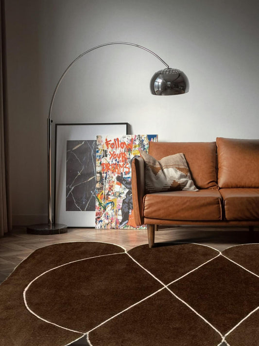 modern brown wool rug and leather sofa in a living room with a floor lamp and artwork on the wall.