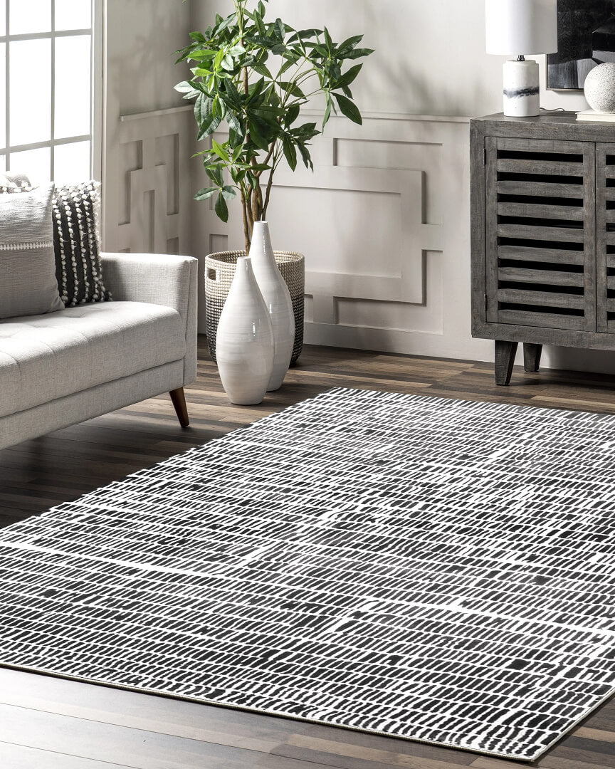 Living room with a black and white hand tufted patterned silk rug, gray sofa, and decorative items.