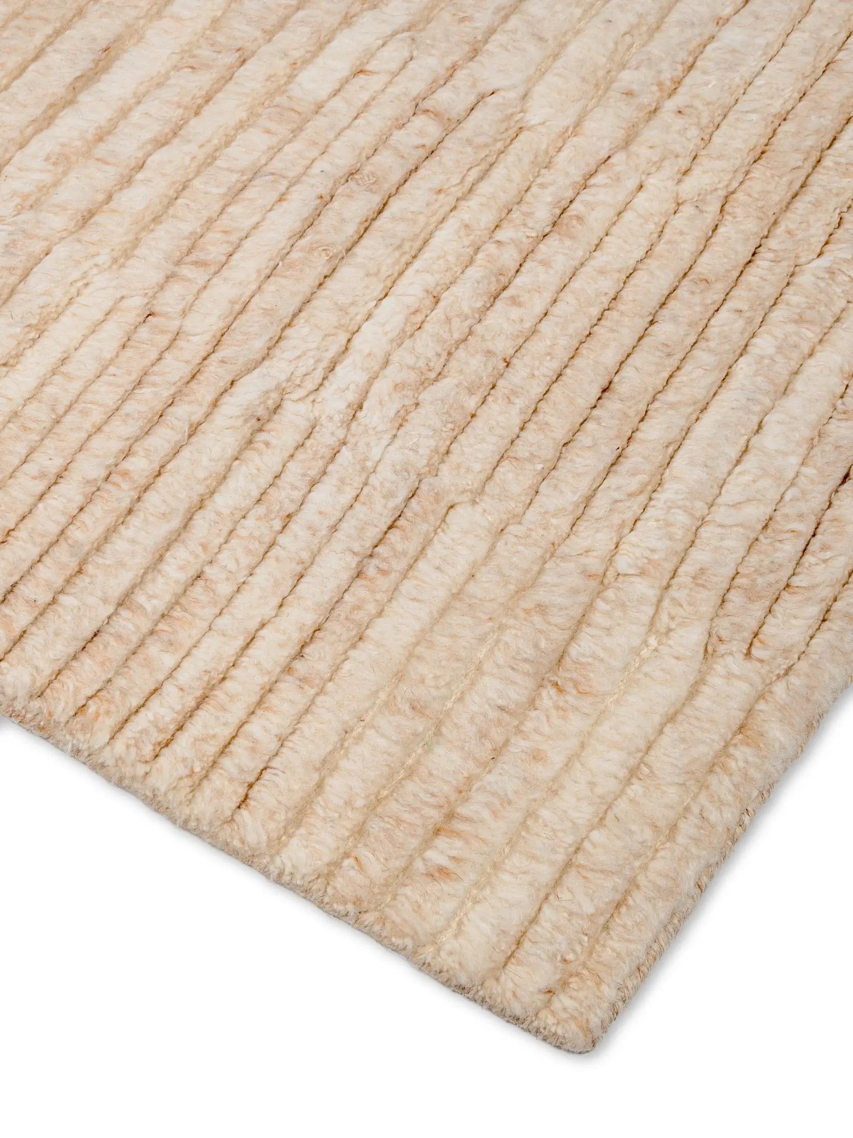 Close-up of a beige textured wool rug corner, hand knotted