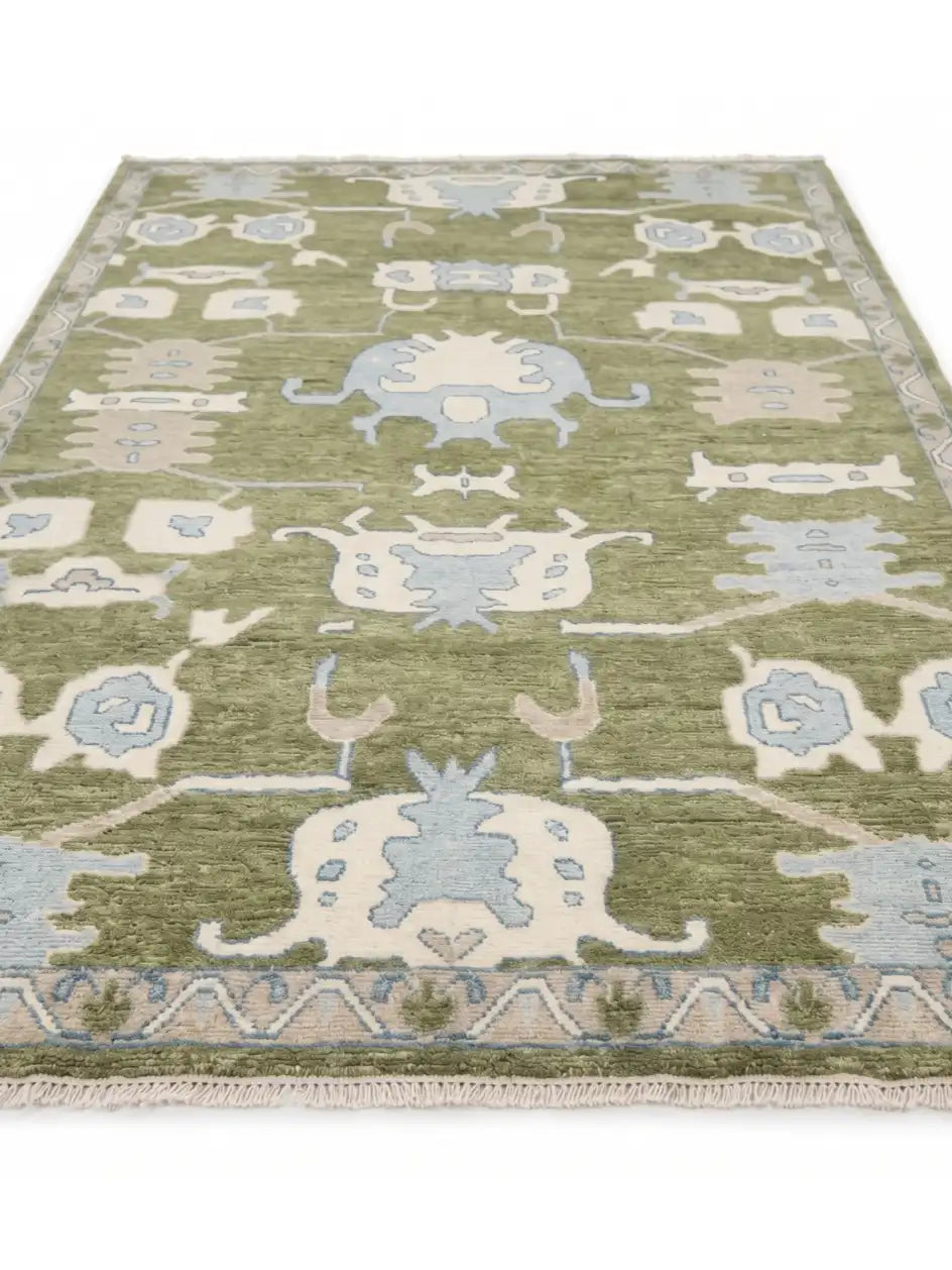 a knotted area rug with a traditional tribal pattern in sage green