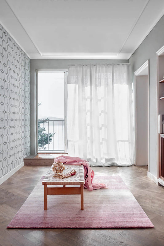 Modern interior with hand wovwn wool rug, wooden coffee table, and white curtains