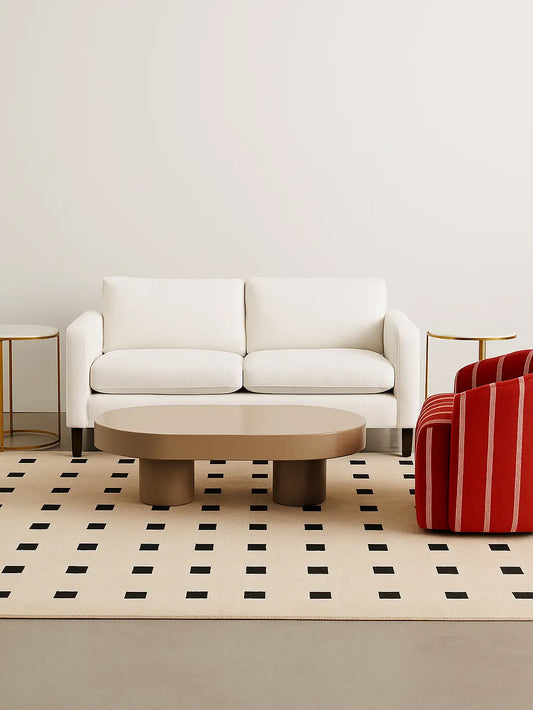 Modern living room with a modern beige and black wool rug, a white sofa, round wooden coffee table, and red striped chair.