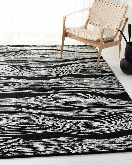 Hand tufted black wool rug with white wave design and a wooden chair on it.