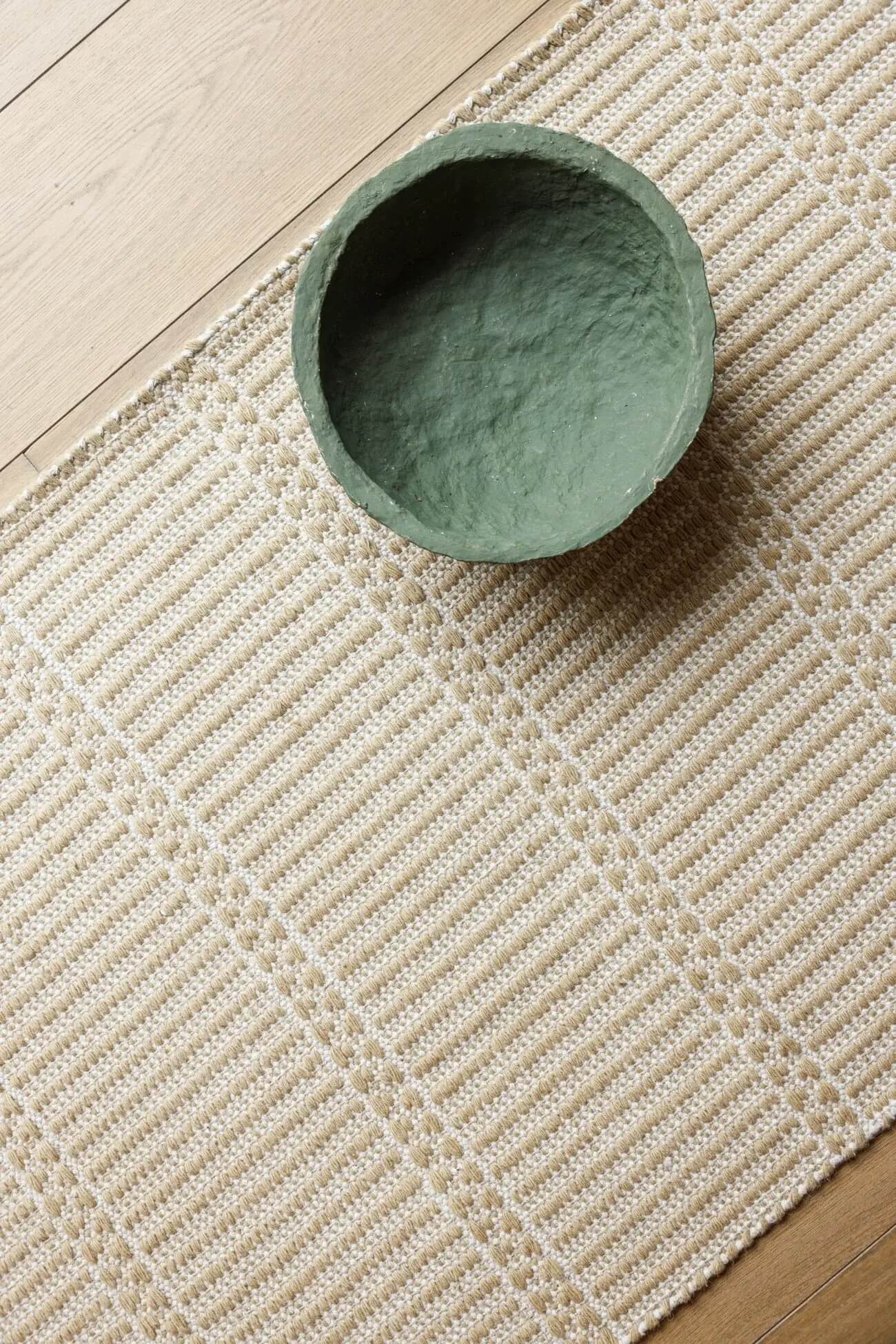 Green ceramic bowl on a beige hand woven wool runner