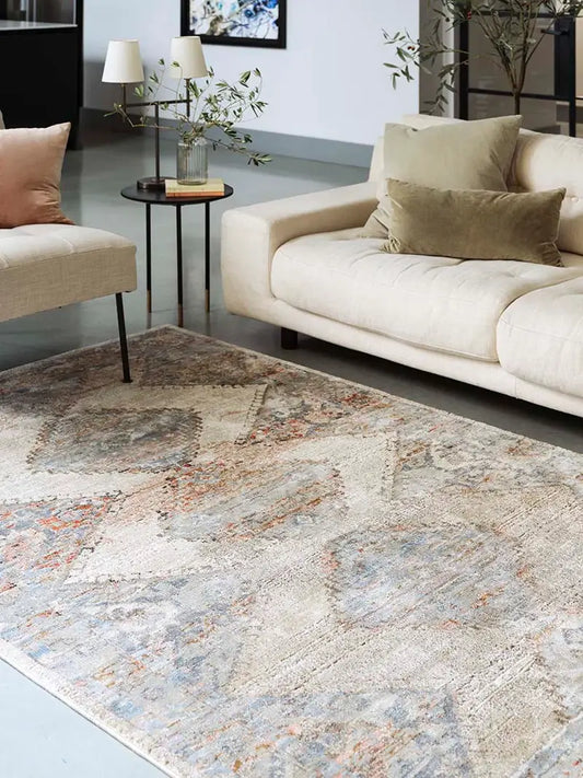 Living room with a traditional hand knotted patterned rug, beige sofa, and side table.