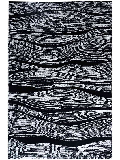 A rectangular area rug with an abstract wavy pattern in black and white